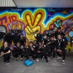 rainbow team group photo standing in front of graffiti wall