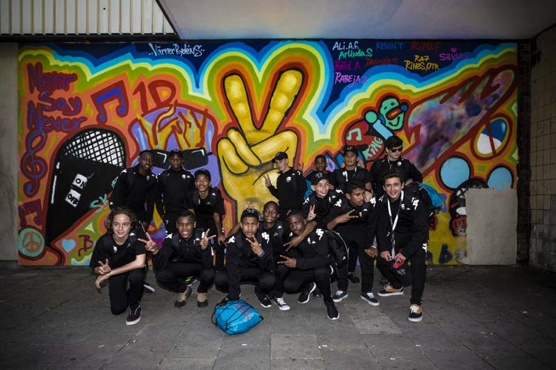 rainbow team group photo standing in front of graffiti wall